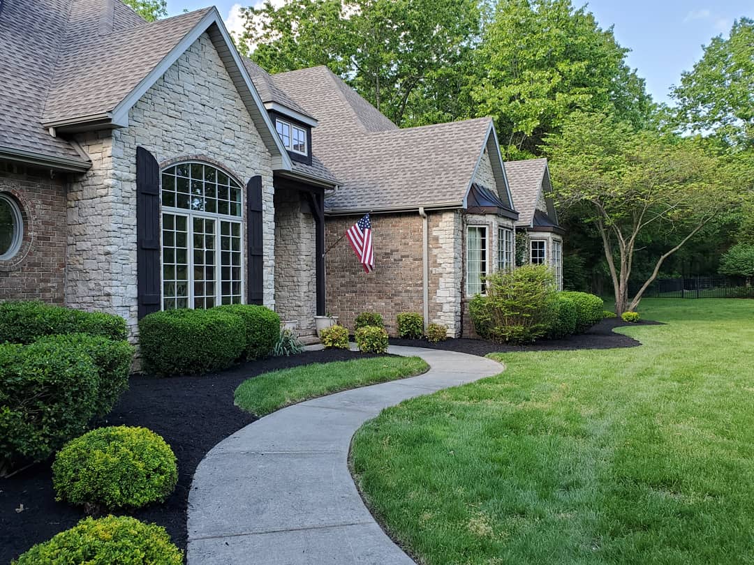 Stone house with a curved walkway and mulched shrub beds