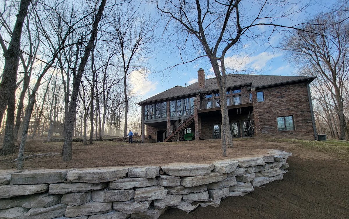 Stacked stone retaining wall beside a brick house