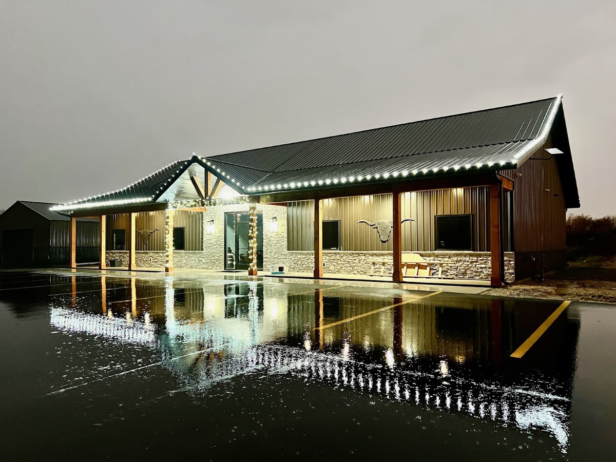 Barn-style building outlined in roofline lights at night